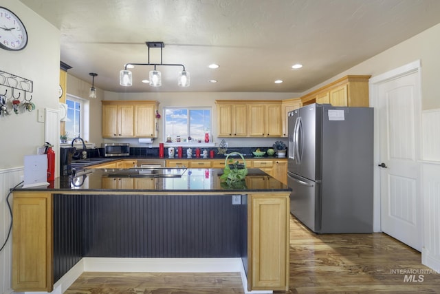 kitchen with sink, hardwood / wood-style flooring, appliances with stainless steel finishes, kitchen peninsula, and pendant lighting