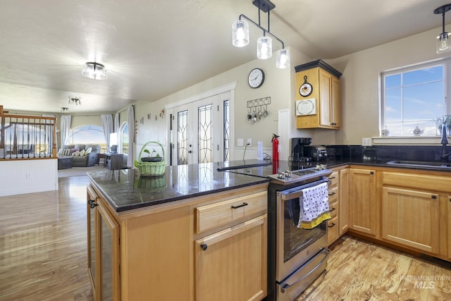 kitchen with sink, light hardwood / wood-style flooring, stainless steel electric range oven, hanging light fixtures, and a kitchen bar