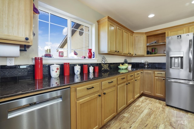 kitchen featuring light hardwood / wood-style floors, stainless steel appliances, and dark stone counters