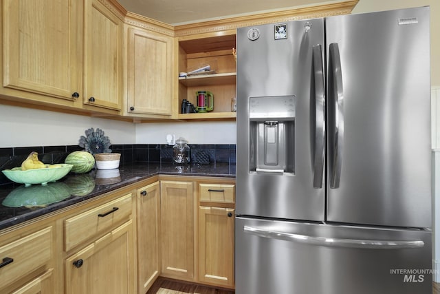 kitchen featuring stainless steel fridge, light brown cabinetry, and dark stone countertops