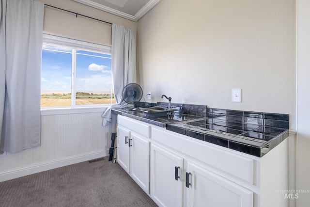 kitchen featuring white cabinetry, ornamental molding, carpet flooring, and sink