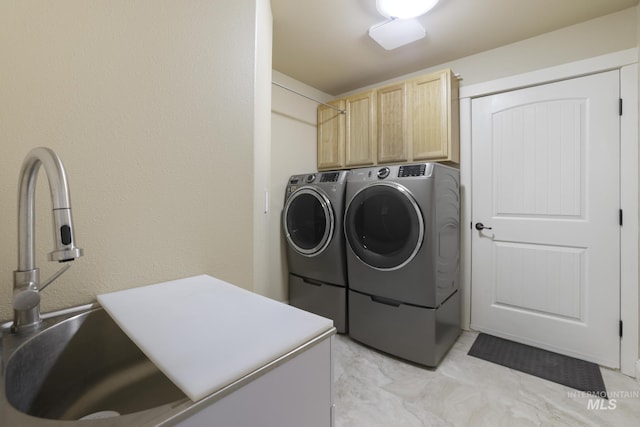 clothes washing area featuring cabinets, washing machine and clothes dryer, and sink