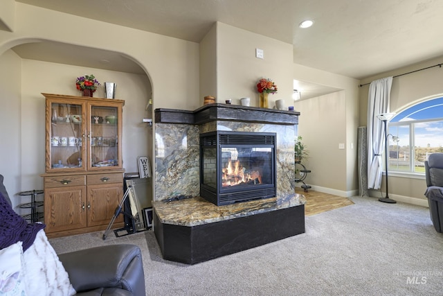 carpeted living room featuring a multi sided fireplace