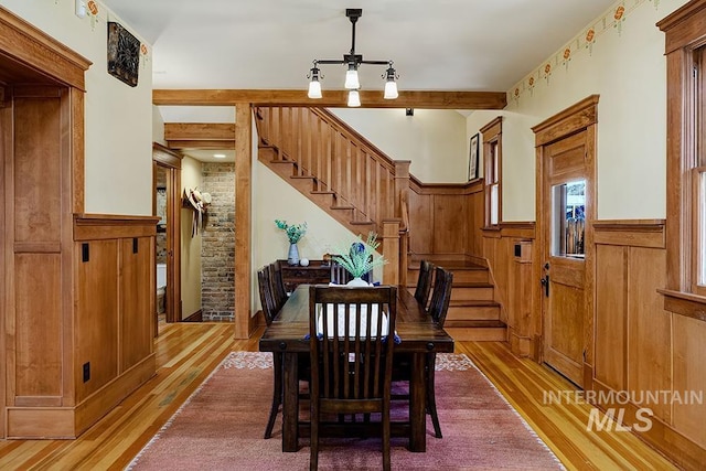 dining area with a ceiling fan, light wood-style flooring, wainscoting, and stairway