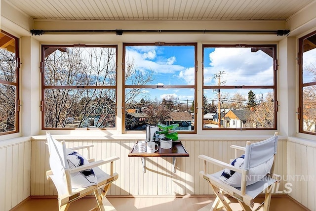 sunroom / solarium featuring a decorative wall, wainscoting, and a wealth of natural light