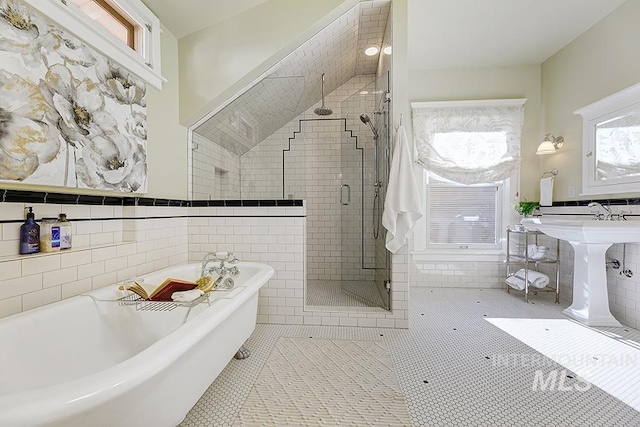 bathroom with a freestanding bath, wainscoting, tile patterned floors, tile walls, and a shower stall