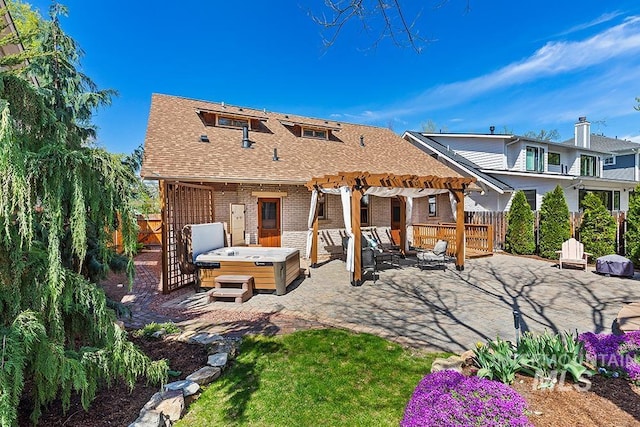 back of house featuring a fenced backyard, a pergola, a hot tub, and a patio