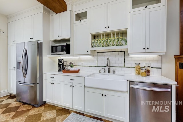 kitchen featuring decorative backsplash, light countertops, white cabinetry, a sink, and stainless steel appliances