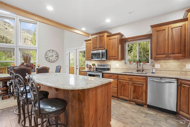 9 Autumn Blaze Ln, Salmon, ID 83467 - kitchen with stainless steel appliances, a sink, a breakfast bar, decorative backsplash, and light stone countertops