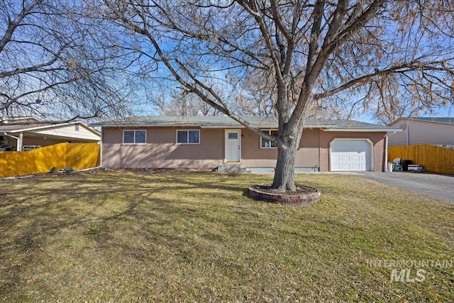 ranch-style home featuring driveway, an attached garage, fence, a front lawn, and stucco siding