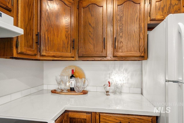 122 N Washington, Moscow, ID 83843 - kitchen featuring freestanding refrigerator, light countertops, under cabinet range hood, and brown cabinets