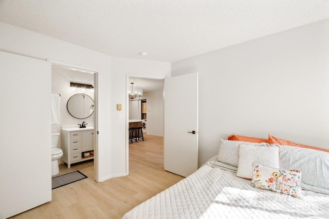 122 N Washington, Moscow, ID 83843 - bedroom with light wood-style floors, ensuite bath, an inviting chandelier, and a sink
