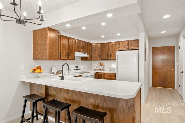 122 N Washington, Moscow, ID 83843 - kitchen featuring under cabinet range hood, light countertops, a peninsula, and white appliances