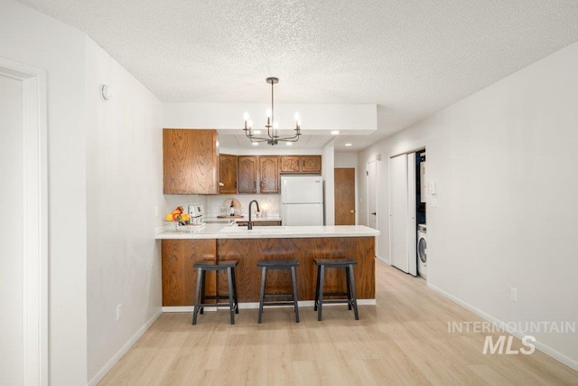 122 N Washington, Moscow, ID 83843 - kitchen featuring freestanding refrigerator, light wood-style flooring, washer / dryer, and an inviting chandelier