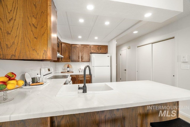 122 N Washington, Moscow, ID 83843 - kitchen with recessed lighting, white appliances, a peninsula, brown cabinets, and light countertops