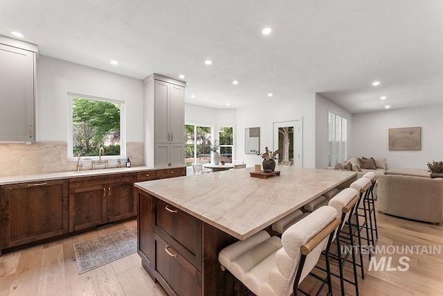 kitchen with a sink, light wood-style floors, recessed lighting, a kitchen bar, and open floor plan