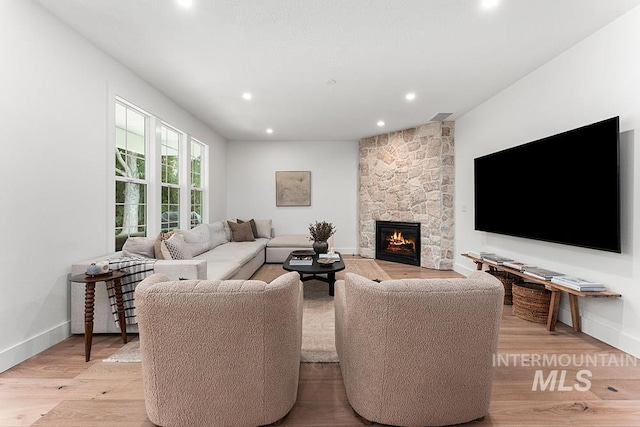 living room featuring recessed lighting, light wood-style floors, a fireplace, and baseboards