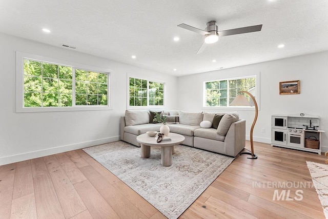 living room featuring light wood-style flooring, baseboards, ceiling fan, and recessed lighting