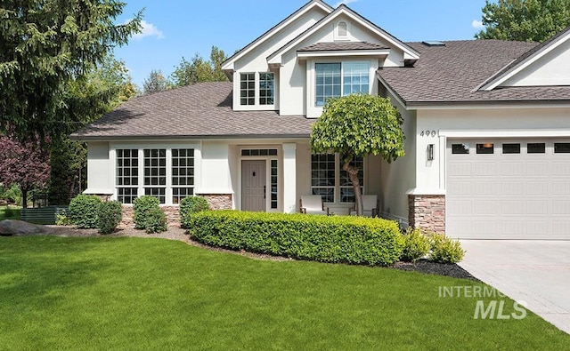 view of front of property featuring stone siding, a garage, a front lawn, and a shingled roof