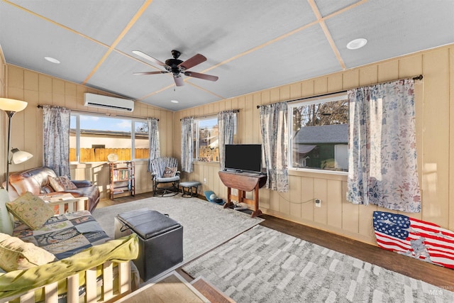 unfurnished living room featuring a wall unit AC, lofted ceiling, ceiling fan, wood-type flooring, and wood walls