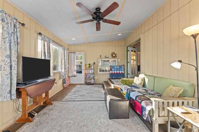 living room featuring wooden walls, vaulted ceiling, ceiling fan, and dark hardwood / wood-style flooring