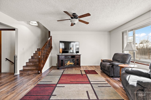 living room featuring ceiling fan, hardwood / wood-style flooring, and a textured ceiling