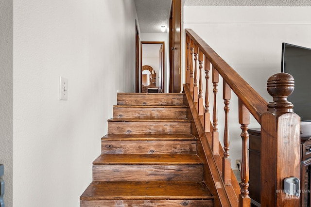 stairs featuring a textured ceiling