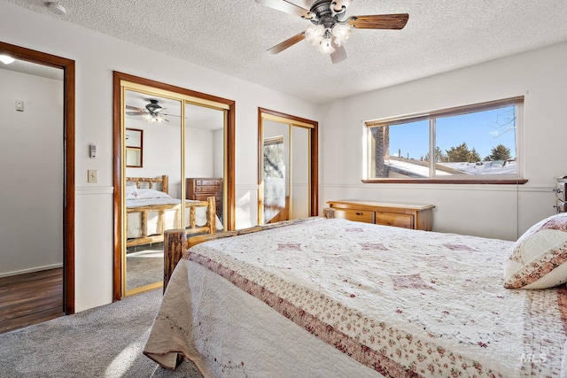 bedroom with multiple closets, ceiling fan, a textured ceiling, and dark colored carpet