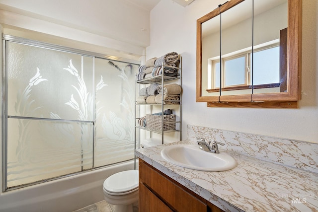 full bathroom featuring vanity, combined bath / shower with glass door, and toilet