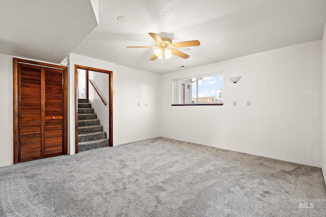 unfurnished room with ceiling fan, carpet floors, and a textured ceiling