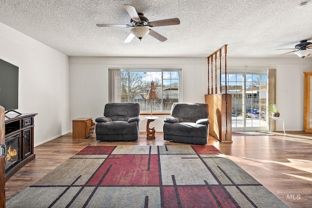 living room with ceiling fan, hardwood / wood-style floors, and a textured ceiling