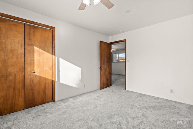 unfurnished bedroom with light colored carpet, a closet, and ceiling fan