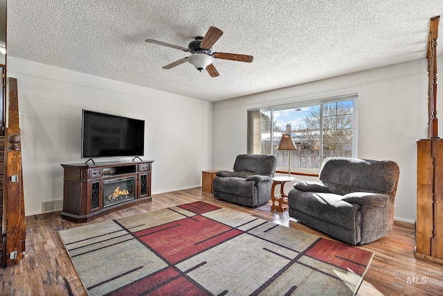 living room with hardwood / wood-style flooring, ceiling fan, and a textured ceiling