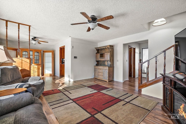 living room with dark wood-type flooring, ceiling fan, and a textured ceiling