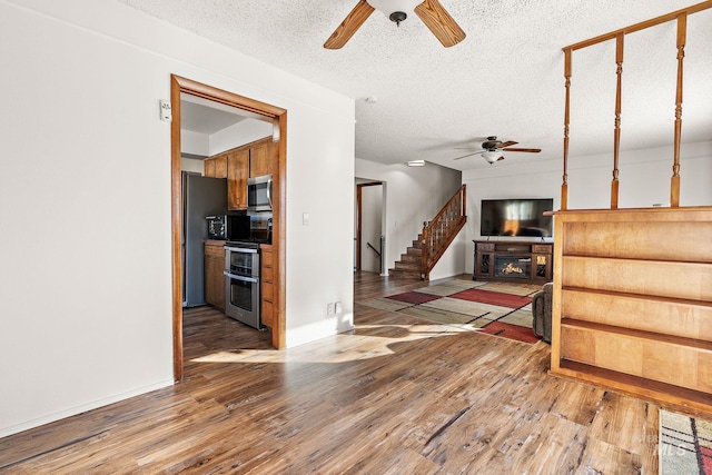 living room with wood-type flooring, a textured ceiling, ceiling fan, and a fireplace