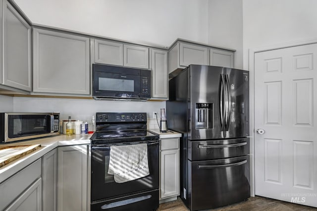 kitchen featuring gray cabinets, black appliances, and dark hardwood / wood-style floors