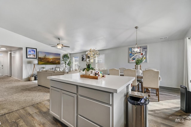 kitchen with vaulted ceiling, a center island, ceiling fan, hanging light fixtures, and hardwood / wood-style flooring