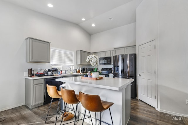 kitchen with a center island, gray cabinets, a breakfast bar area, and black appliances