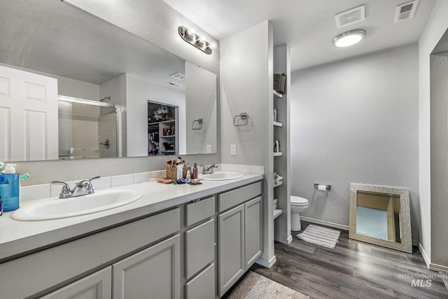 bathroom featuring hardwood / wood-style flooring, an enclosed shower, vanity, and toilet