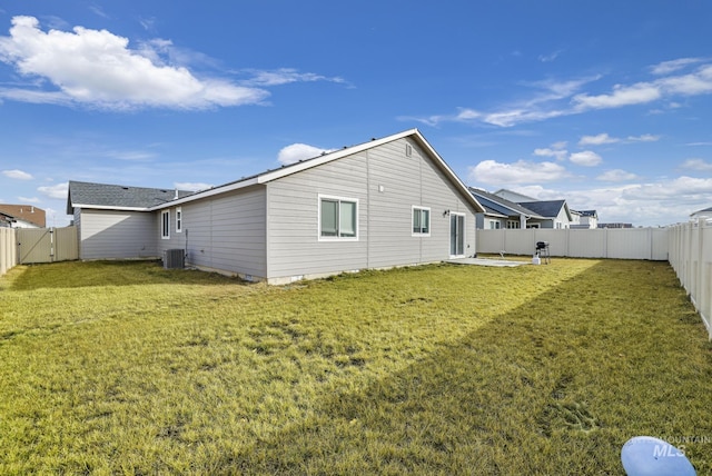 rear view of property with central AC and a lawn