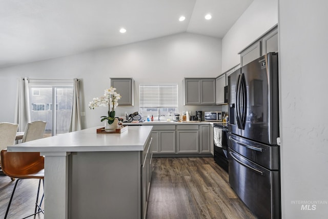 kitchen featuring a center island, appliances with stainless steel finishes, gray cabinetry, and lofted ceiling