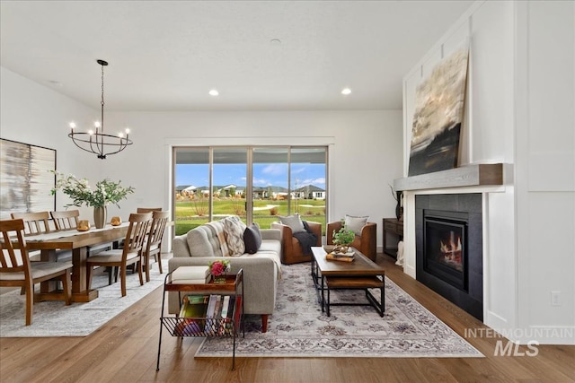 living area featuring recessed lighting, an inviting chandelier, a tile fireplace, and wood finished floors