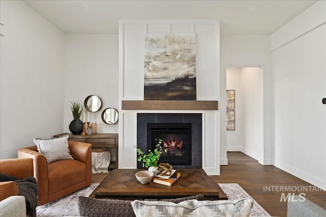 living area featuring baseboards, wood finished floors, and a tile fireplace