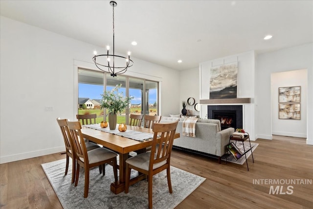 dining room with recessed lighting, a tiled fireplace, wood finished floors, and baseboards