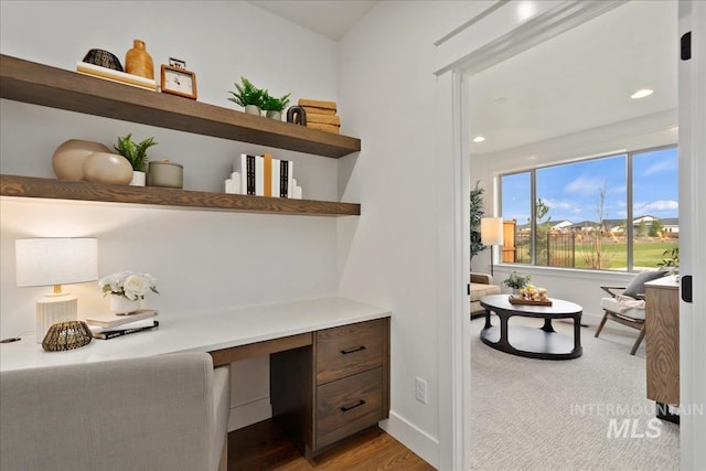 office with built in desk, baseboards, and wood finished floors