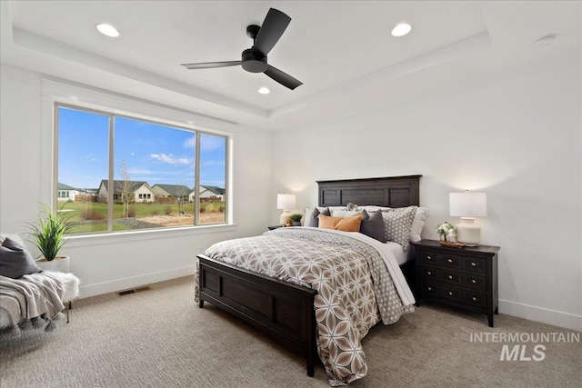 carpeted bedroom with baseboards, visible vents, a raised ceiling, and recessed lighting