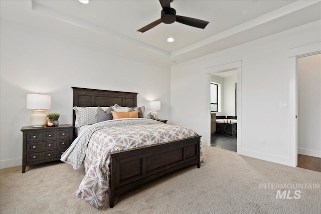 carpeted bedroom with a tray ceiling, ensuite bathroom, baseboards, and recessed lighting