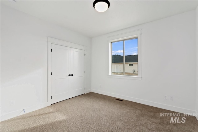 unfurnished bedroom with a closet, carpet, visible vents, and baseboards