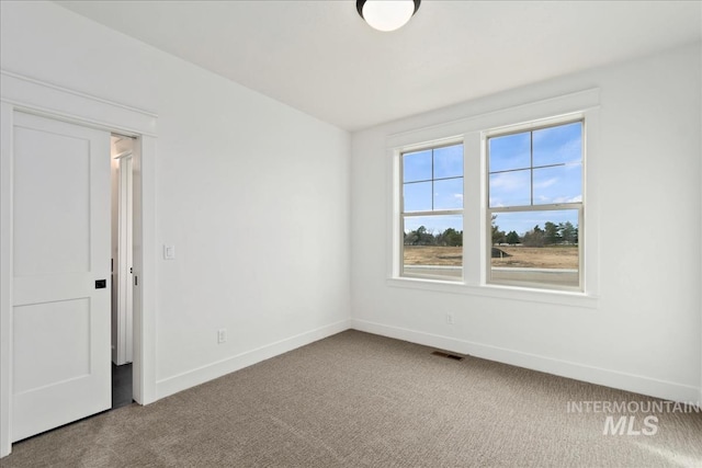 carpeted spare room featuring visible vents and baseboards