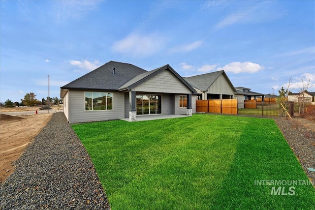 back of property featuring roof with shingles, a patio area, fence, and a lawn